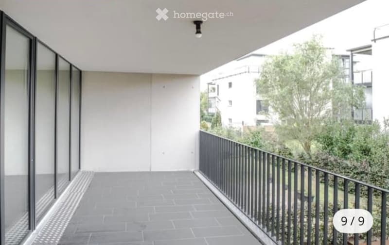 Modern building with glass exterior, concrete flooring, white walls, steel railing, glass walls