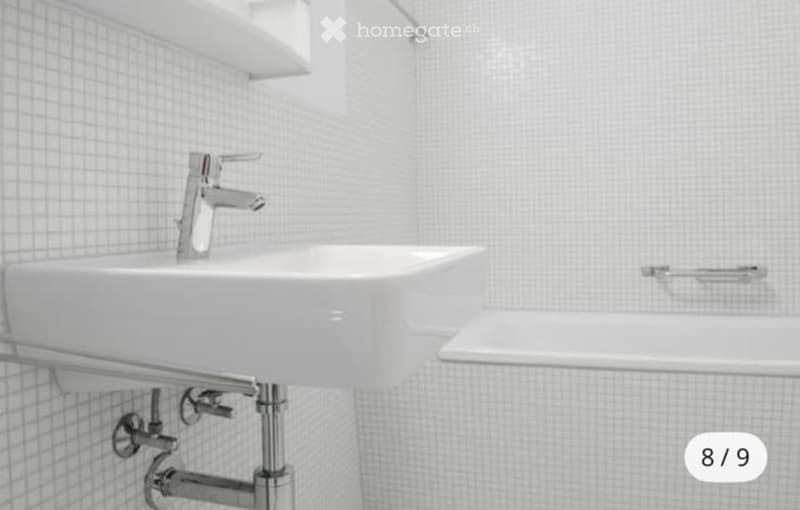 Modern bathroom with a white sink and chrome faucet, white tiled walls, and built-in shelves above the sink.