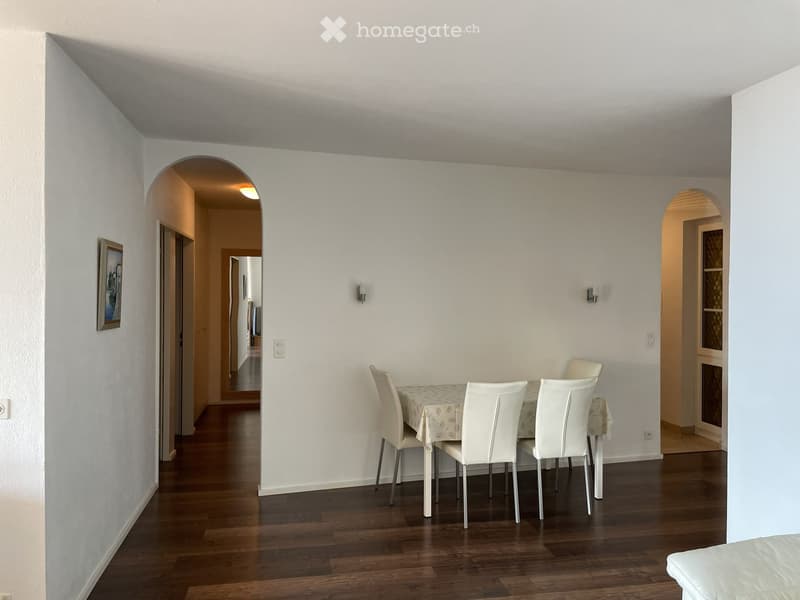 Dining room with wooden flooring, white walls, and a dining table with chairs.
