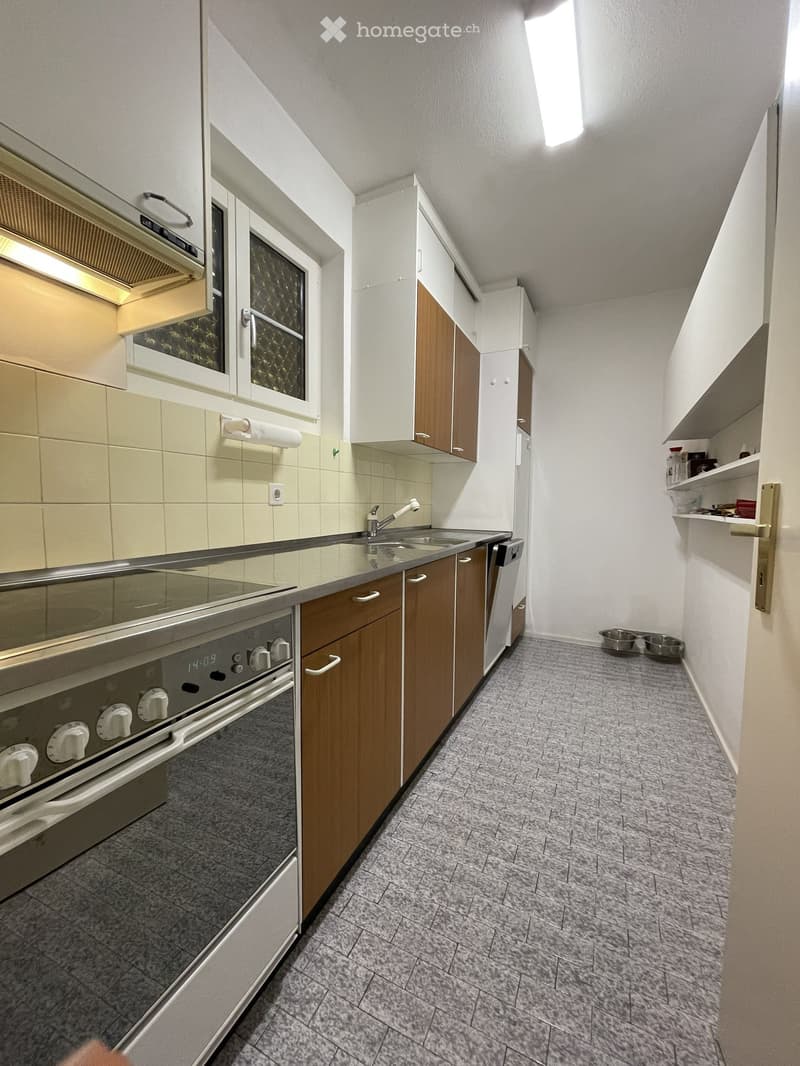 Modern kitchen with wooden cabinets, stainless steel appliances, and a tiled backsplash. Features an oven, microwave, sink, and refrigerator.