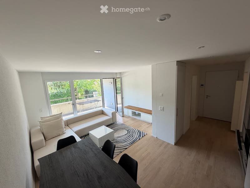 Modern living and dining area with a white sectional sofa, coffee table, dining table with chairs, and a bench near the balcony entrance.