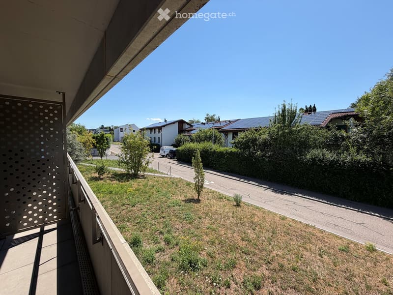 Balcony overlooking a residential area with houses, solar panels, and greenery.