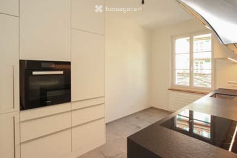 Modern kitchen with white cabinets, a built-in oven, and a stainless steel sink.