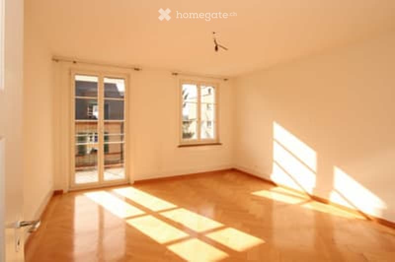 Empty room with wooden flooring, large window, and glass door leading to balcony.