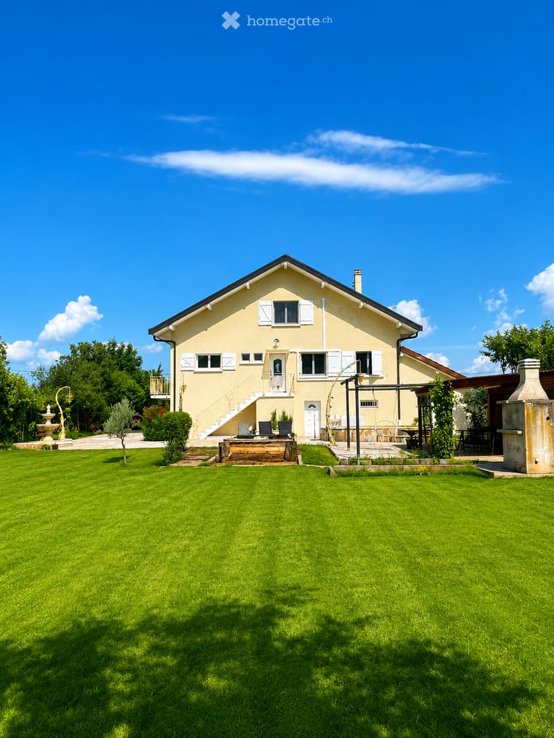 Two-story house with light yellow walls, white shutters, and a well-maintained lawn in front.