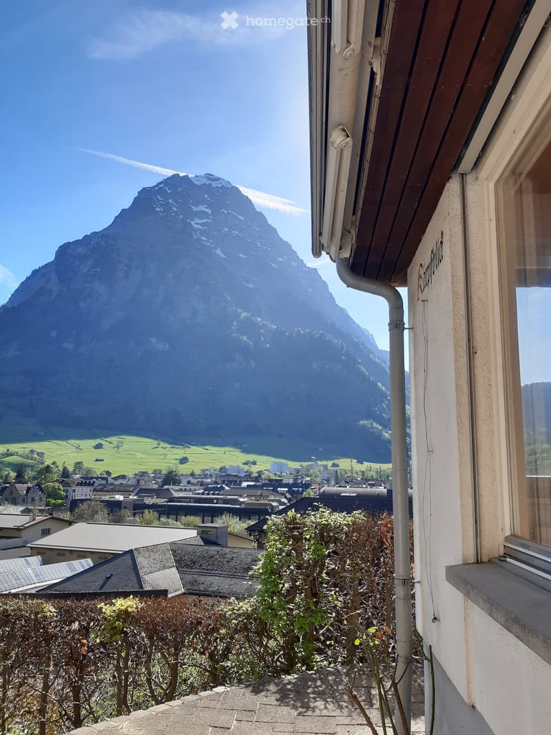 Balcony overlooking a town with a mountain backdrop, featuring a clear view of the landscape and surrounding buildings.