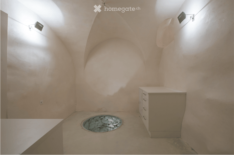 An unfurnished room with arched walls, a small sink, and a circular opening in the floor.