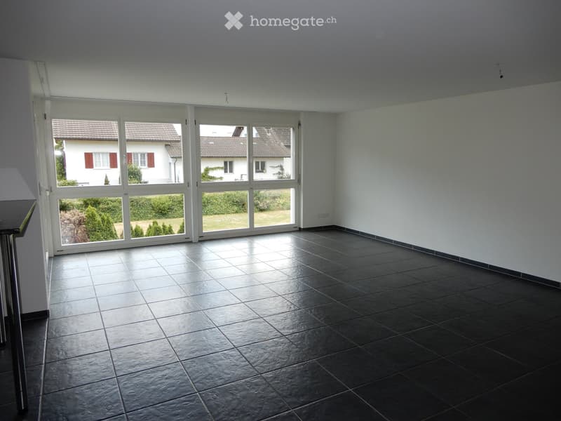 Empty room with dark tiled floor, large windows, and white walls. No furniture or equipment visible.