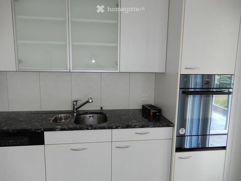 Modern kitchen with white cabinets, granite countertop, double sink, and built-in dishwasher.