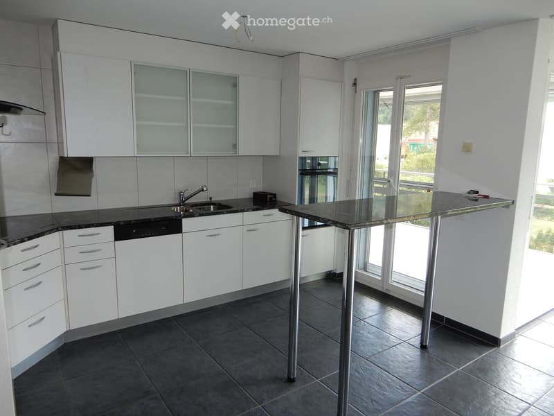 Modern kitchen with white cabinets, stainless steel appliances, and a central island with a black countertop.
