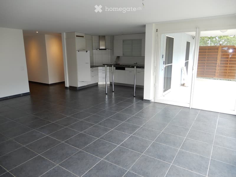 Empty room with dark grey tiled floor, white walls, and a doorway leading to an outdoor area. The room is unfurnished with no visible furniture or equipment.