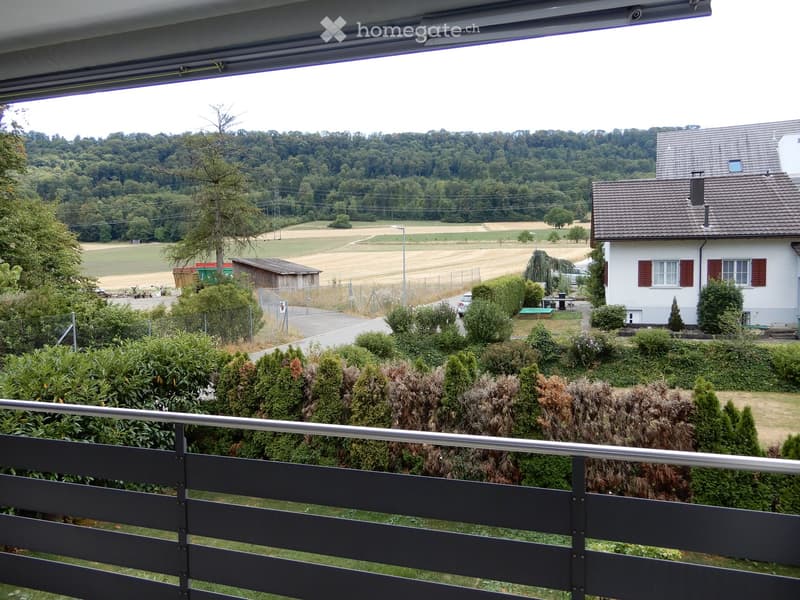 Balcony overlooking a rural landscape with fields, trees, and a nearby house.