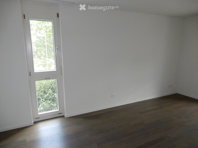 Empty room with wooden flooring, white walls, and a white door with glass panels leading outside.