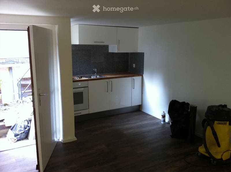 Empty kitchen with white cabinets, wooden countertops, and a sink. The floor is wooden, and the space is unfurnished with no visible appliances or furniture.