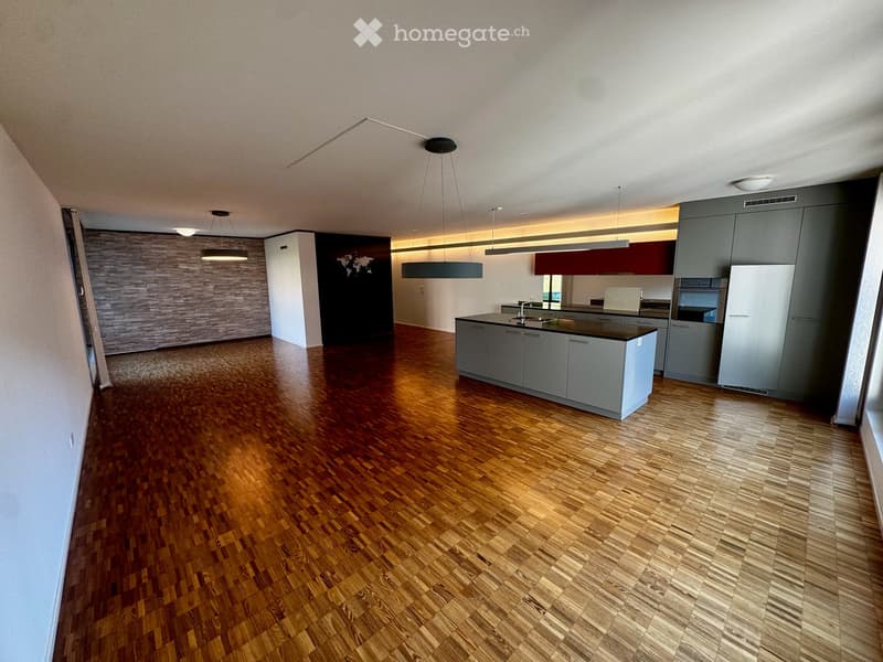Modern kitchen with grey cabinets, a central island, and wooden flooring.