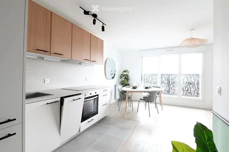 Modern kitchen with white cabinets, stainless steel appliances, a dining table with chairs, and a large window with a view.