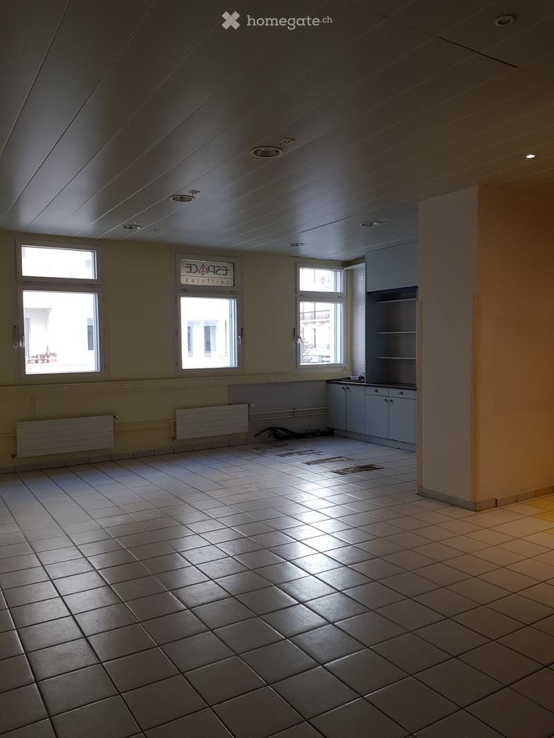 Empty room, white tiled floor, windows, wall cabinets, metal radiators