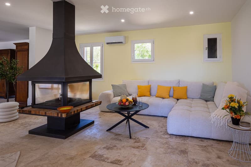 Modern living room with a large sectional sofa, fireplace, coffee table, side table, and decorative items.