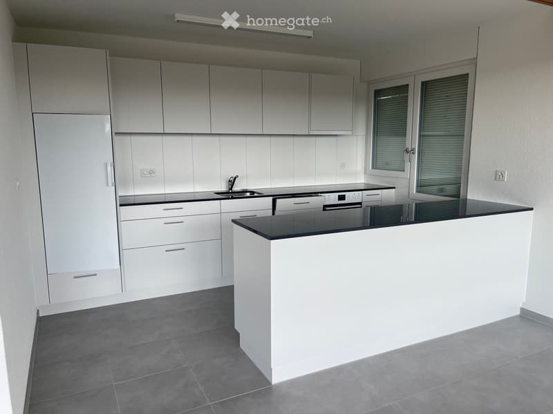 Modern kitchen with white cabinets, black countertop, and stainless steel appliances including a sink, faucet, and oven.