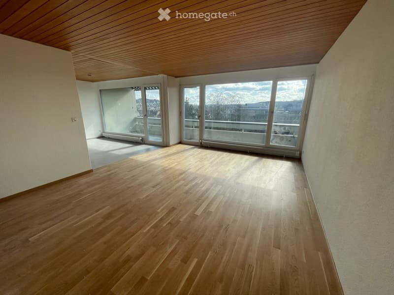 Empty room with wooden flooring, large windows, and a wooden ceiling.