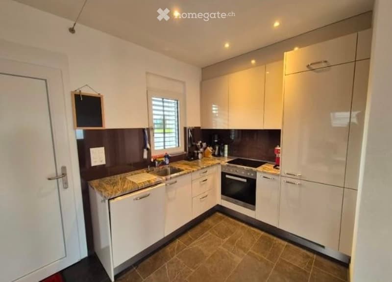 Modern kitchen with white cabinets, granite countertop, stainless steel appliances, and a window above the sink.