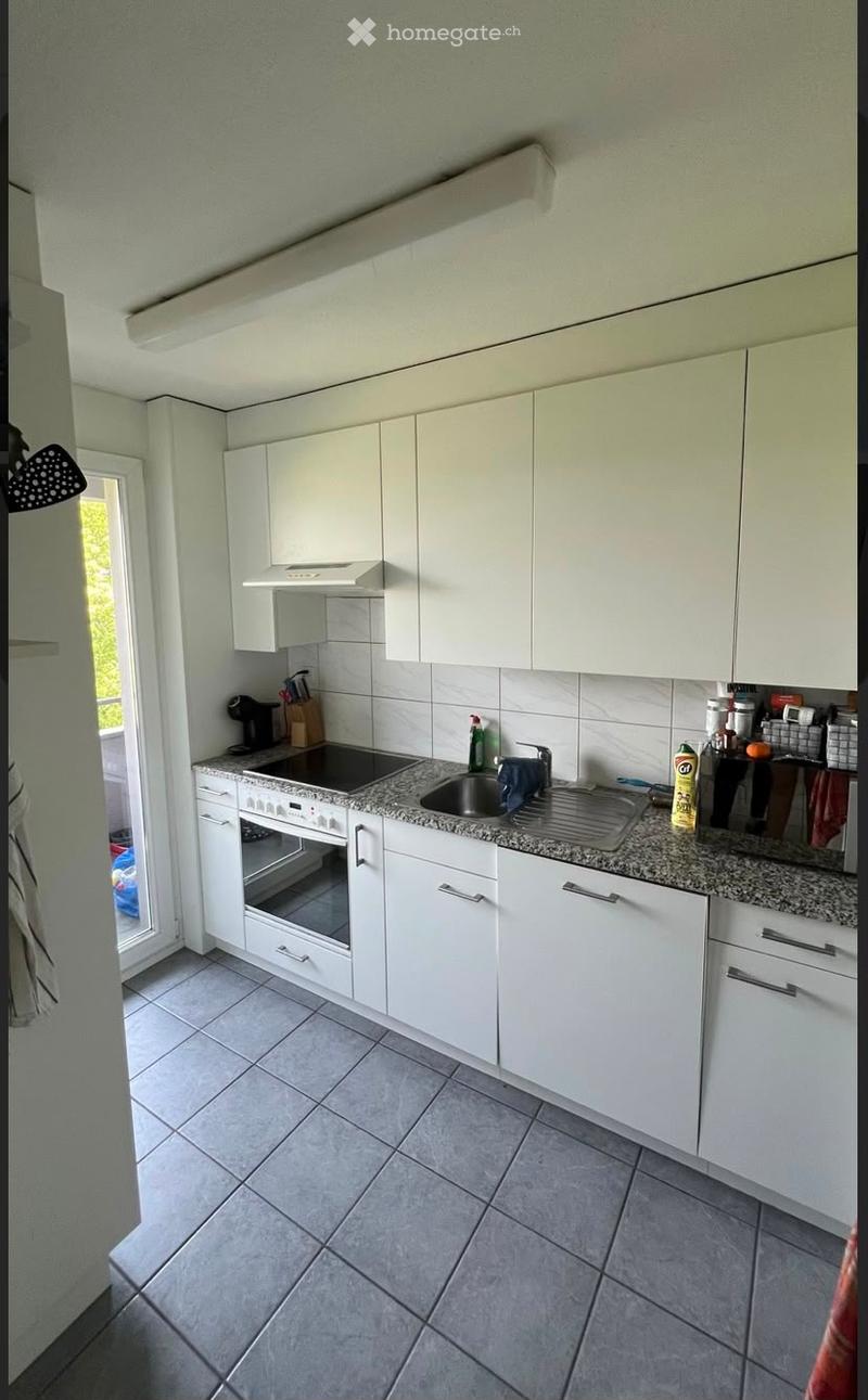 Modern kitchen with white cabinets, granite countertop, built-in oven, and stainless steel sink.
