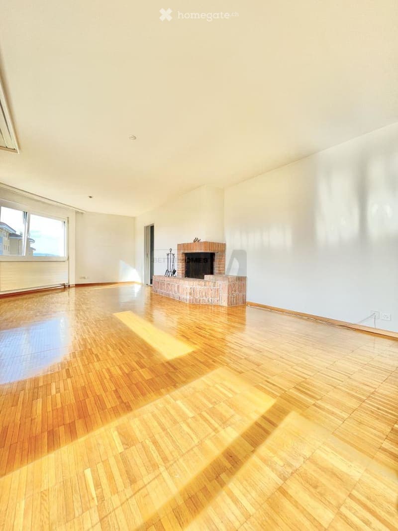 Empty room with wooden flooring, white walls, and a brick fireplace. No furniture or equipment present.