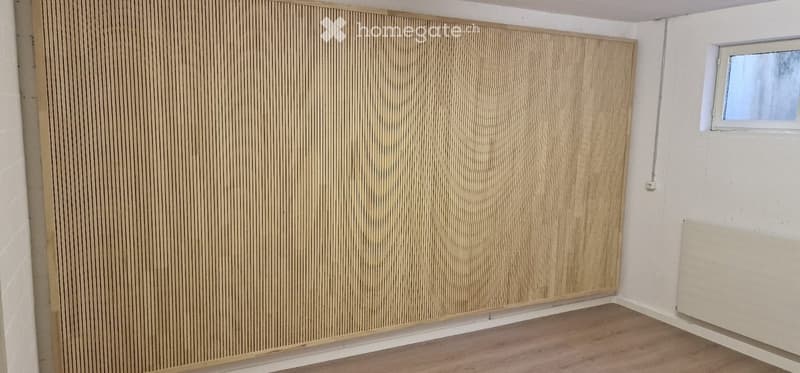 Empty room with wooden flooring, white walls, and a small window. No furniture or equipment present.