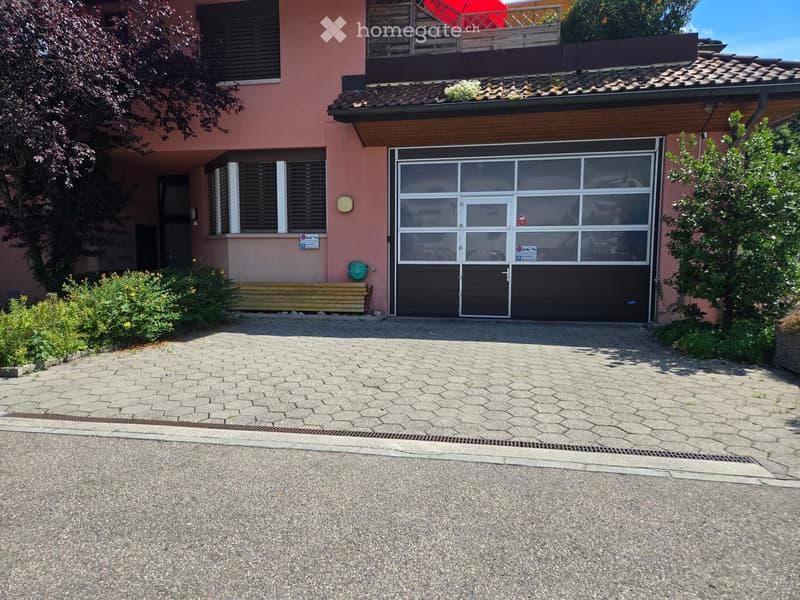 Two-story house with a large garage, pink exterior, and a balcony on the upper floor.