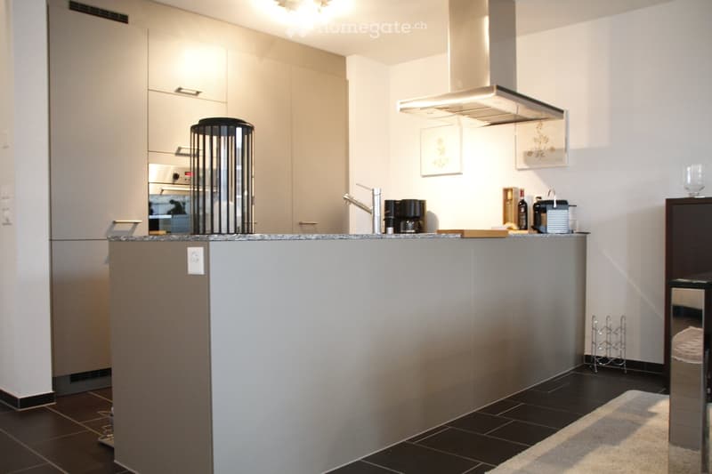 Modern kitchen with white cabinets, stainless steel appliances, and a central island with a granite countertop.