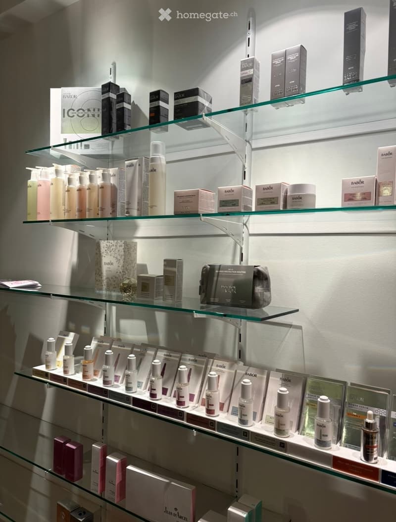 A display of skincare products on glass shelves, including bottles, boxes, and a small bag.