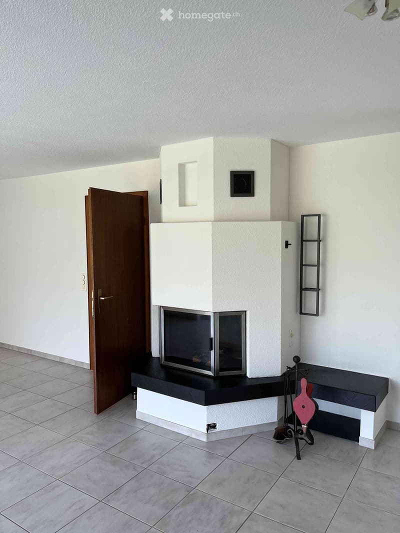 Modern hallway with a built-in fireplace, white walls, tiled floor, and a wooden door leading to another room.