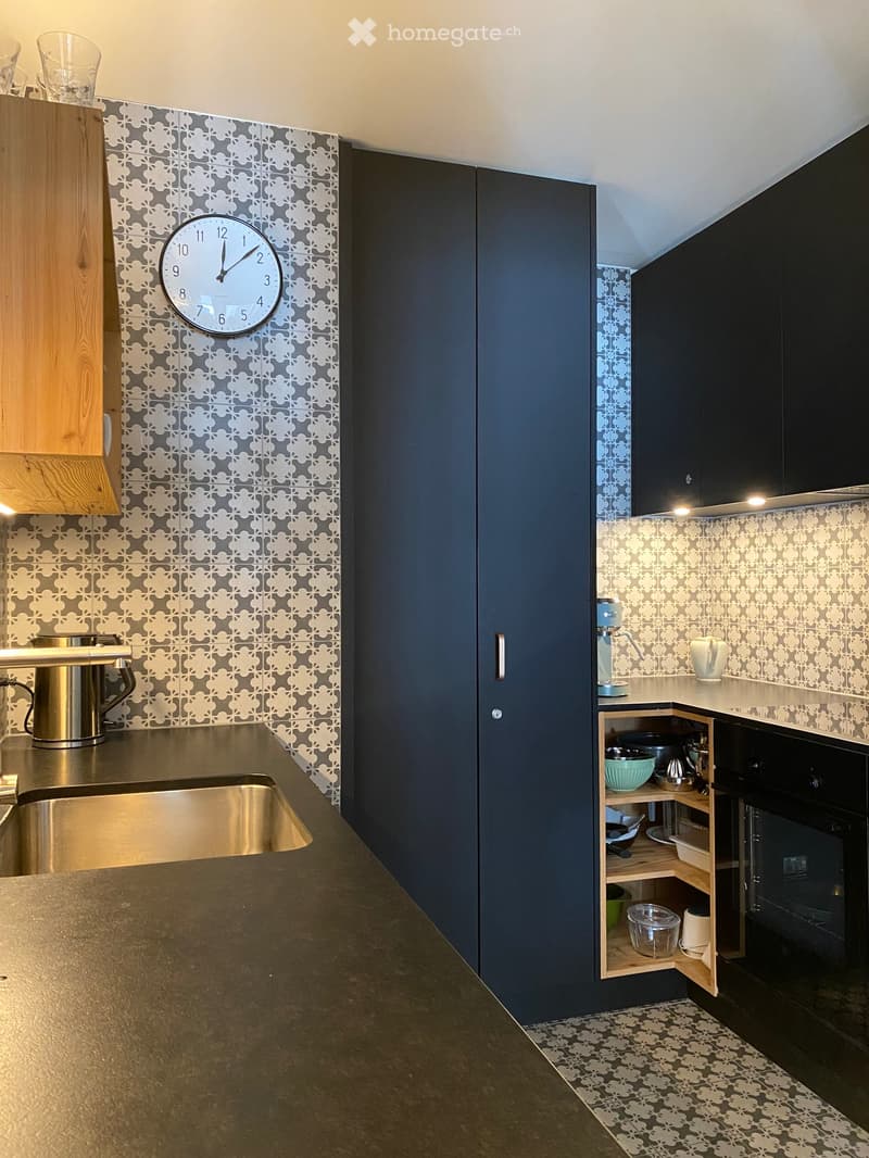 Modern kitchen with dark blue cabinets, stainless steel sink, coffee maker, and decorative patterned tiles.