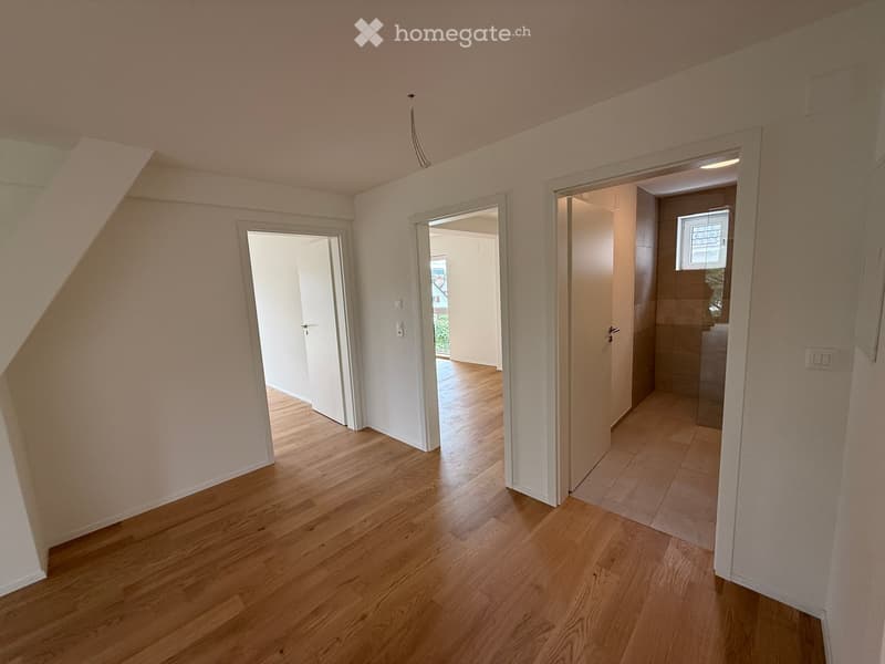 Empty hallway with wooden flooring, white walls, and open doors leading to other rooms.
