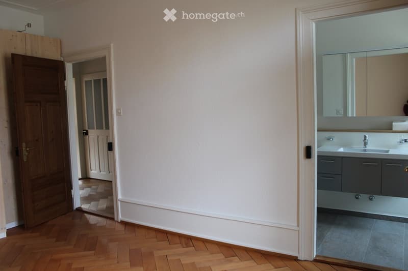Bathroom with modern sink, mirror, and cabinet. The room has light-colored walls and wooden flooring.