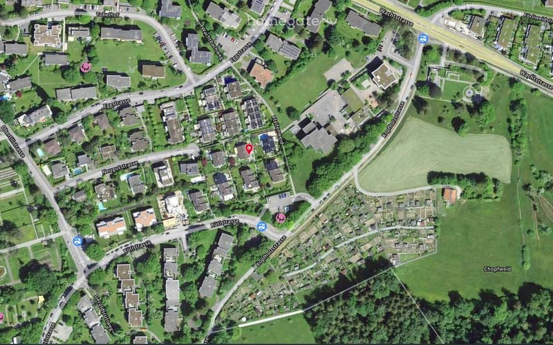Aerial view of a residential area with multiple houses, streets, and green spaces.