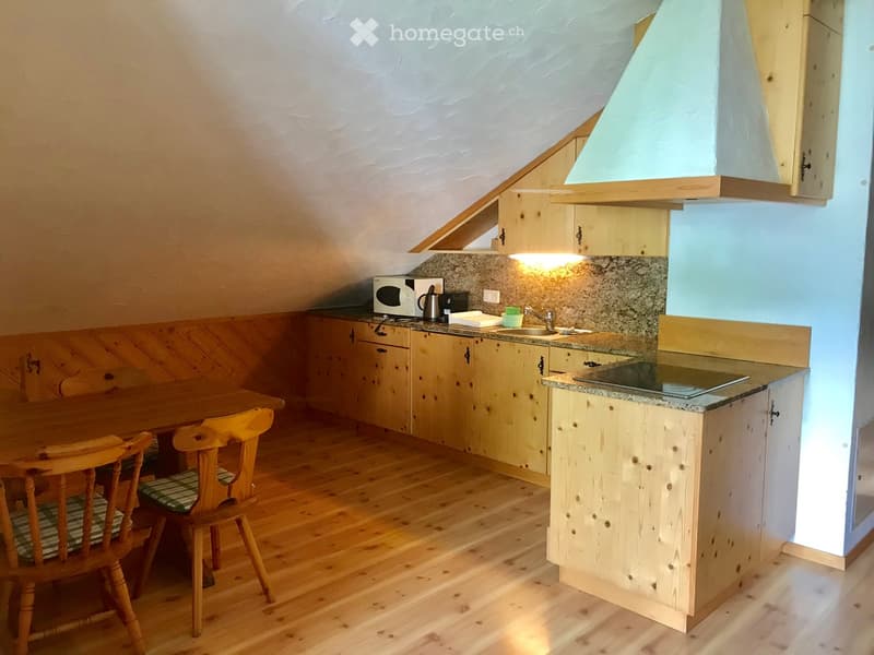 Cozy kitchen with wooden cabinets, granite countertop, microwave, sink, and a small dining area with a wooden table and chairs.