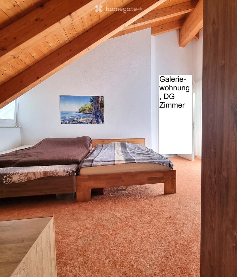Cozy attic bedroom with wooden beams, two single beds, and a painting on the wall.
