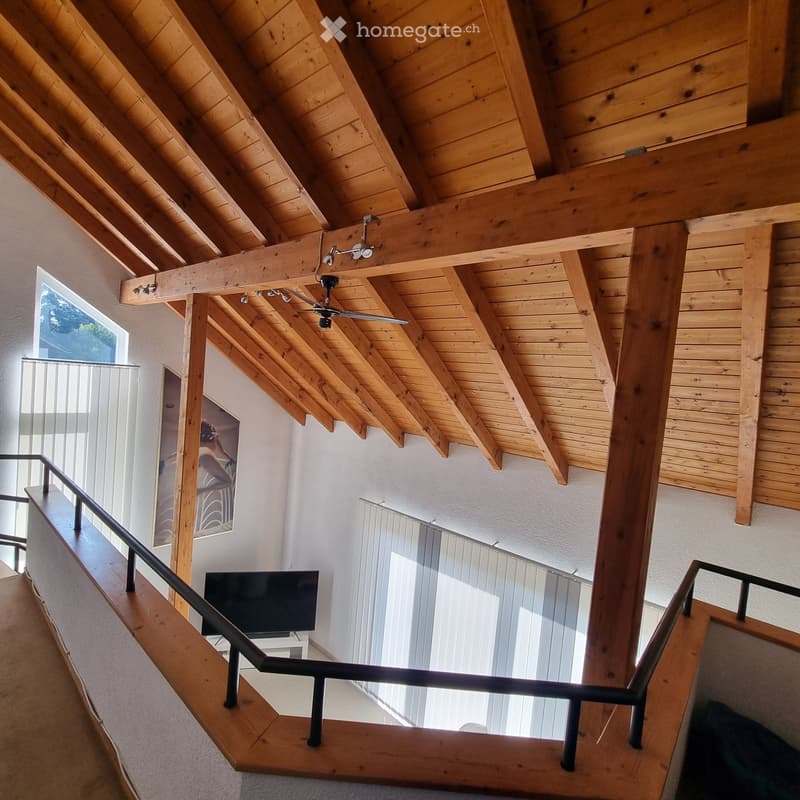 Spacious hallway with wooden ceiling beams, modern staircase, and large windows allowing natural light to fill the space.