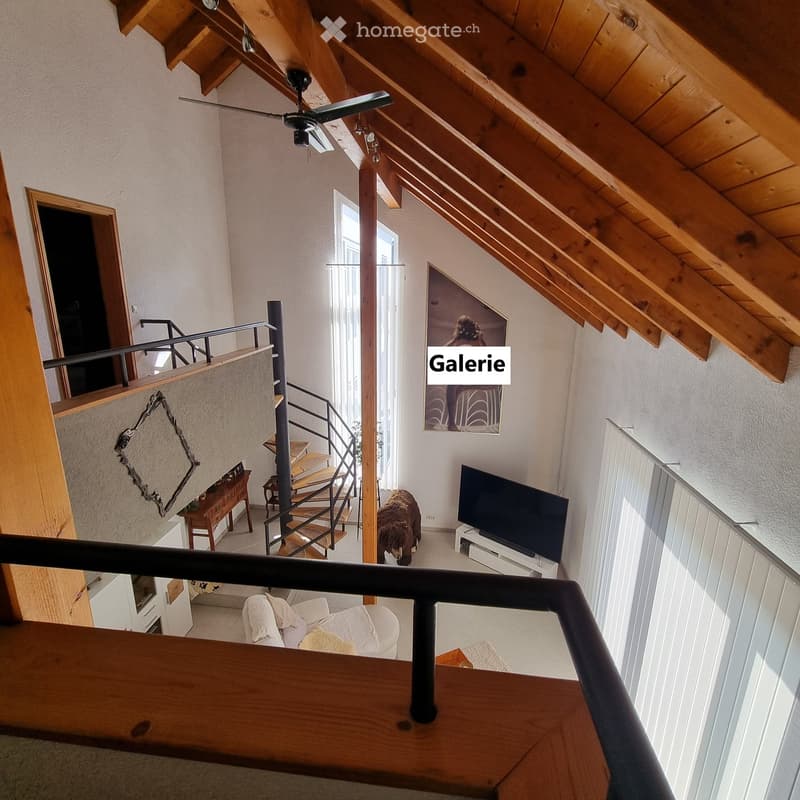 A modern living room with a wooden ceiling, white walls, a staircase leading to an upper level, a sofa, a television, a small table, and a picture frame on the wall.