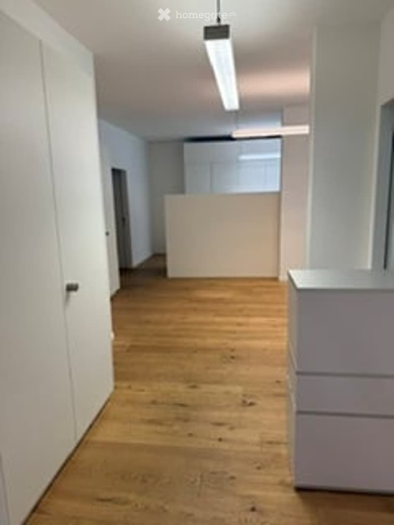 Completely empty room with light wooden flooring, white walls, and modern white cabinetry. No furniture or equipment present.
