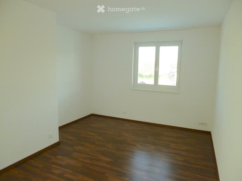 Empty room with wooden flooring and white walls, featuring a single window with white frame and two panes.