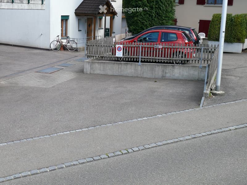 {"type": "Parking place", "objects": [], "description": "Parking area with a red car, bicycle, and a small wooden fence separating it from the street.", "localized_descriptions": {"EN": "Parking area with a red car, bicycle, and a small wooden fence separ