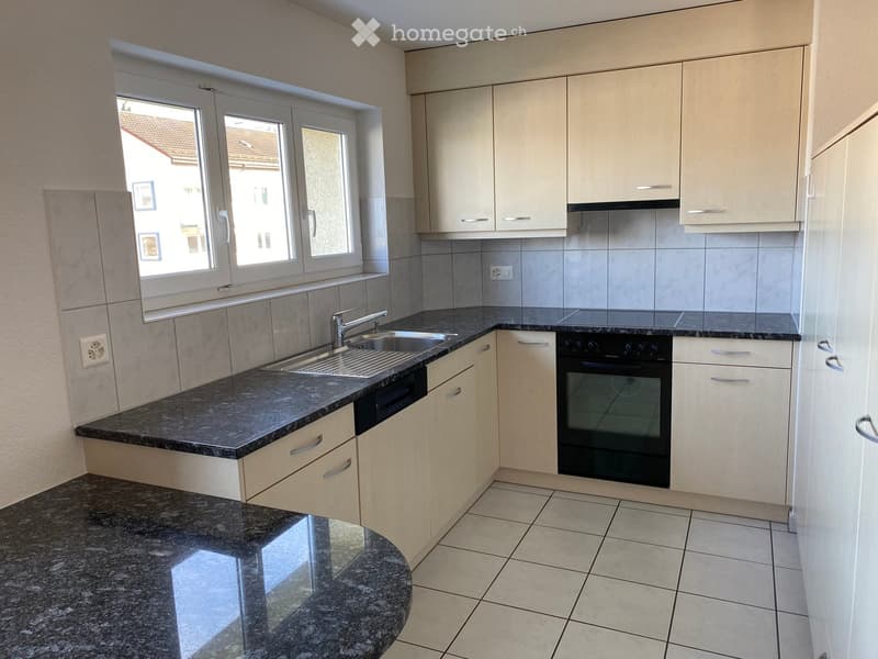 Modern kitchen with white tiled floor, granite countertop, silver faucet, black oven and dishwasher