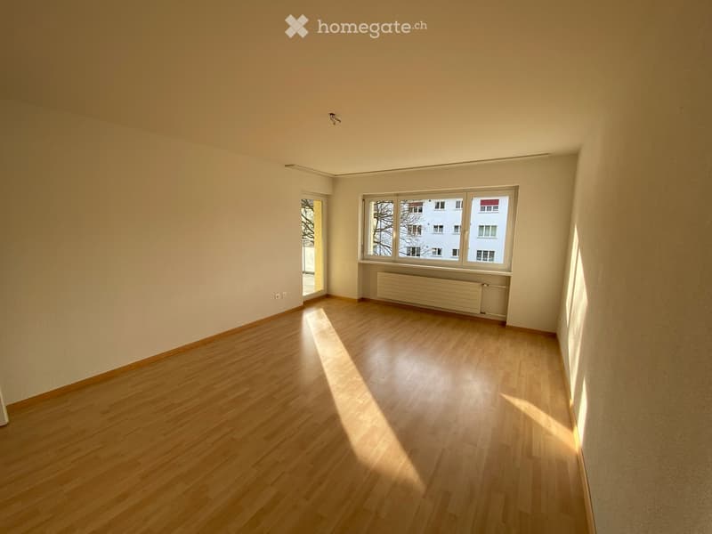 Empty room with white walls, wooden floor, windows, and radiators