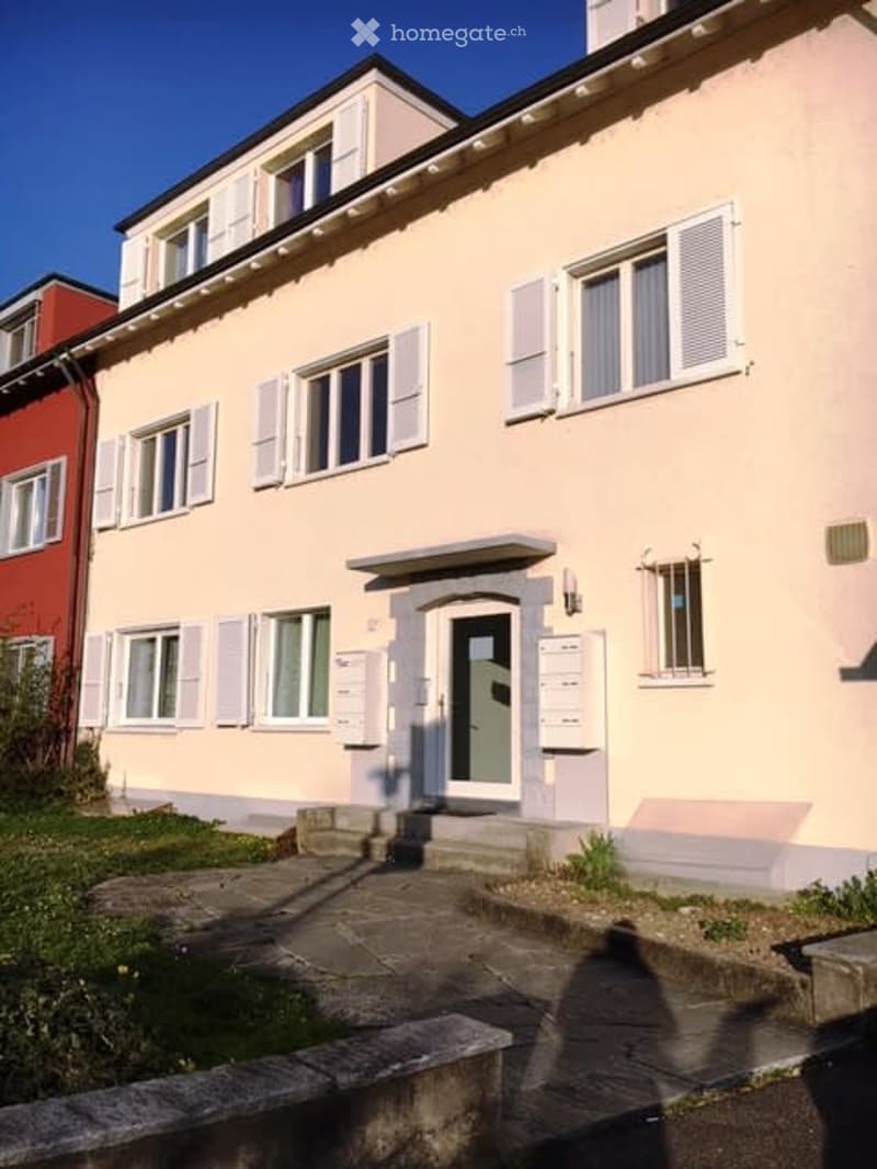 Two story apartment building, pink and red paint, white windows, outdoor mailbox