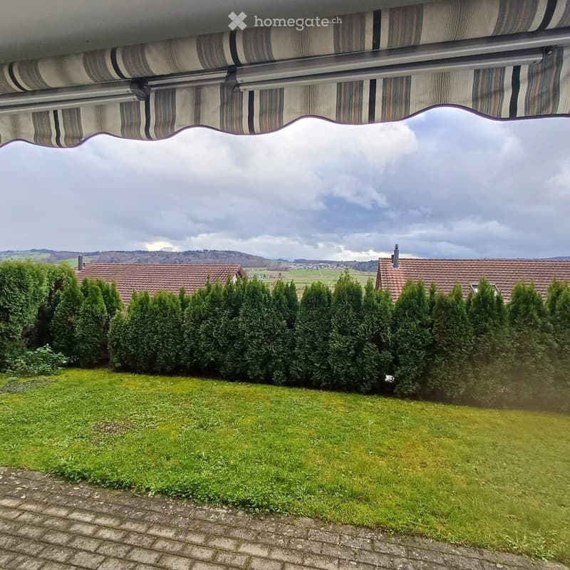 Garden / Outdoor Area. A well-maintained garden with neatly trimmed hedges, a grassy lawn, and a view of surrounding houses and countryside under a partly cloudy sky.