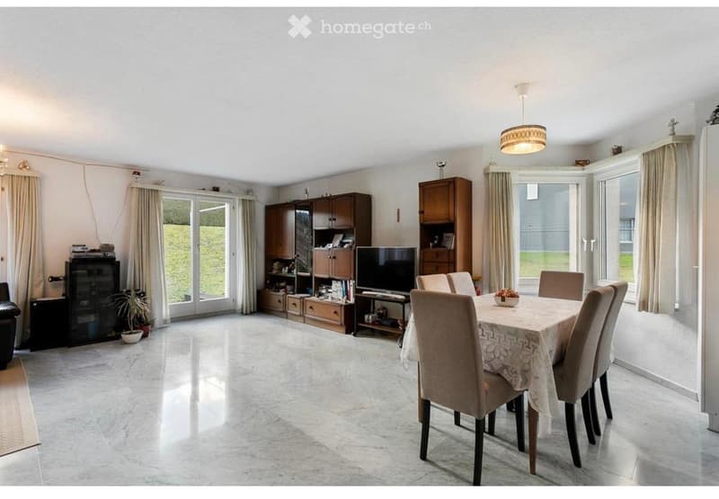 Bright dining room with large windows, marble flooring, a dining table with chairs, a TV, and wooden cabinets.