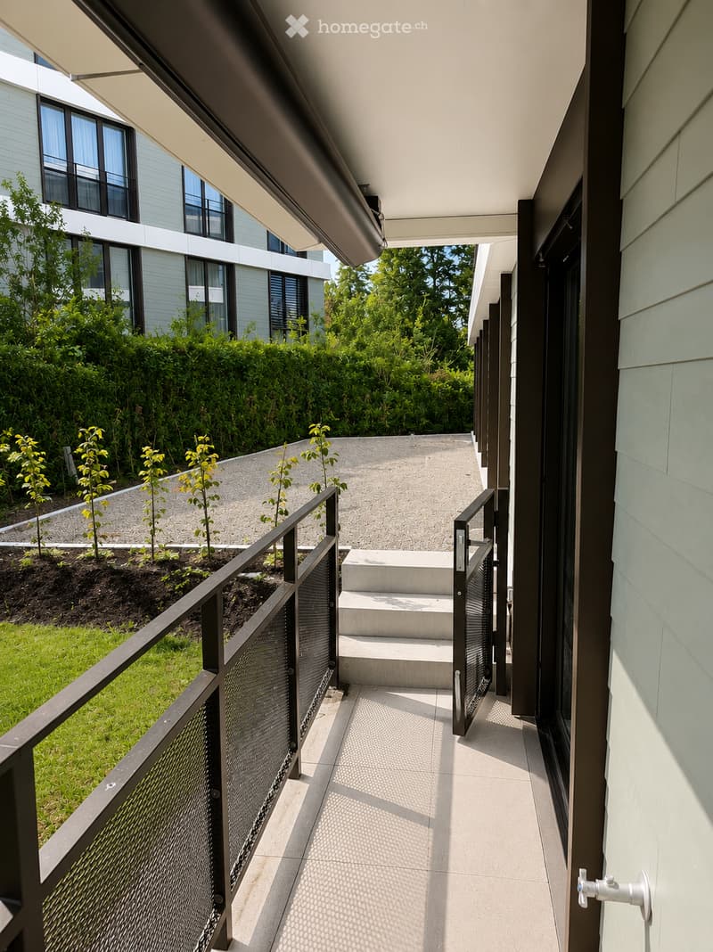 Modern covered walkway with concrete steps leading to a raised garden area, featuring a metal railing and lush greenery.