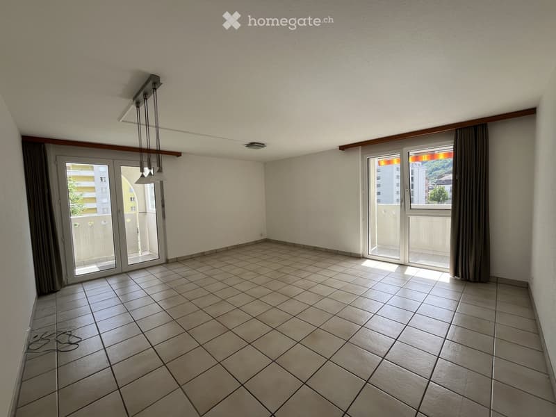 Empty room with tiled floor, large windows, and sliding glass doors leading to a balcony.